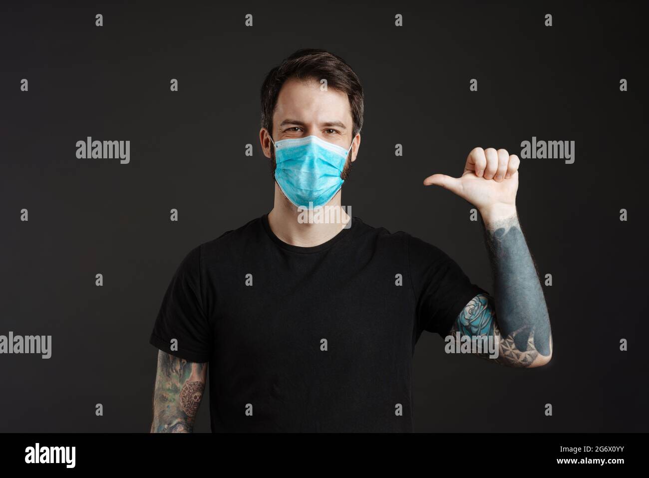 White brunette man in face mask posing and pointing finger at himself ...