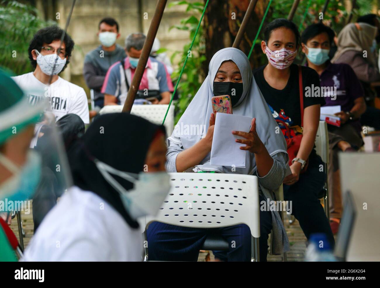 People wearing protective face masks queue up for the coronavirus disease (COVID-19) vaccine, as the Indonesia government speeds up its inoculation effort by deploying a mobile vaccine van, in Jakarta, Indonesia, July 8, 2021. Picture taken July 8, 2021. REUTERS/Ajeng Dinar Ulfiana Stock Photo