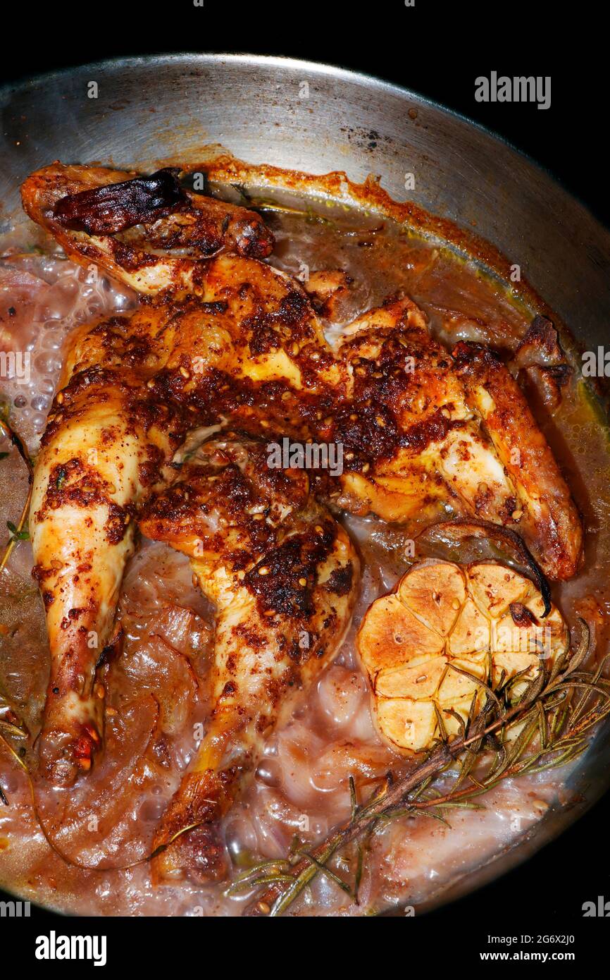 oven roasted baby chicken with onions and galic in a pan, dish known as spatchcock Stock Photo