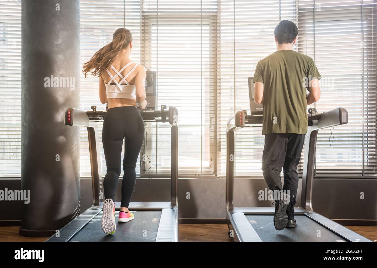 Treadmill Rear View Full length rear view of young man and woman running on treadmills ...