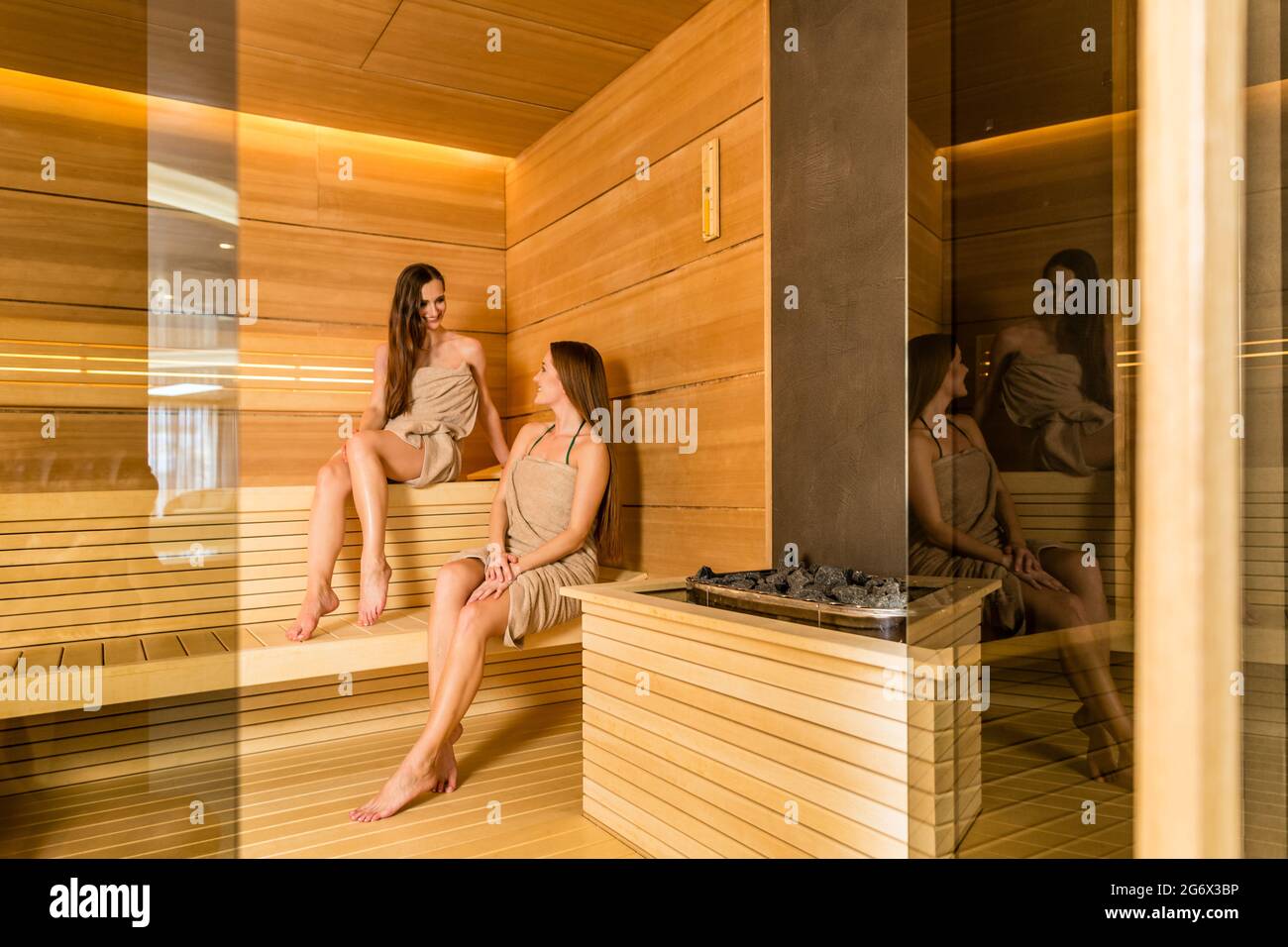 Full length of two female best friends smiling while enjoying the therapeutic effect of a dry sauna in a modern wellness center Stock Photo