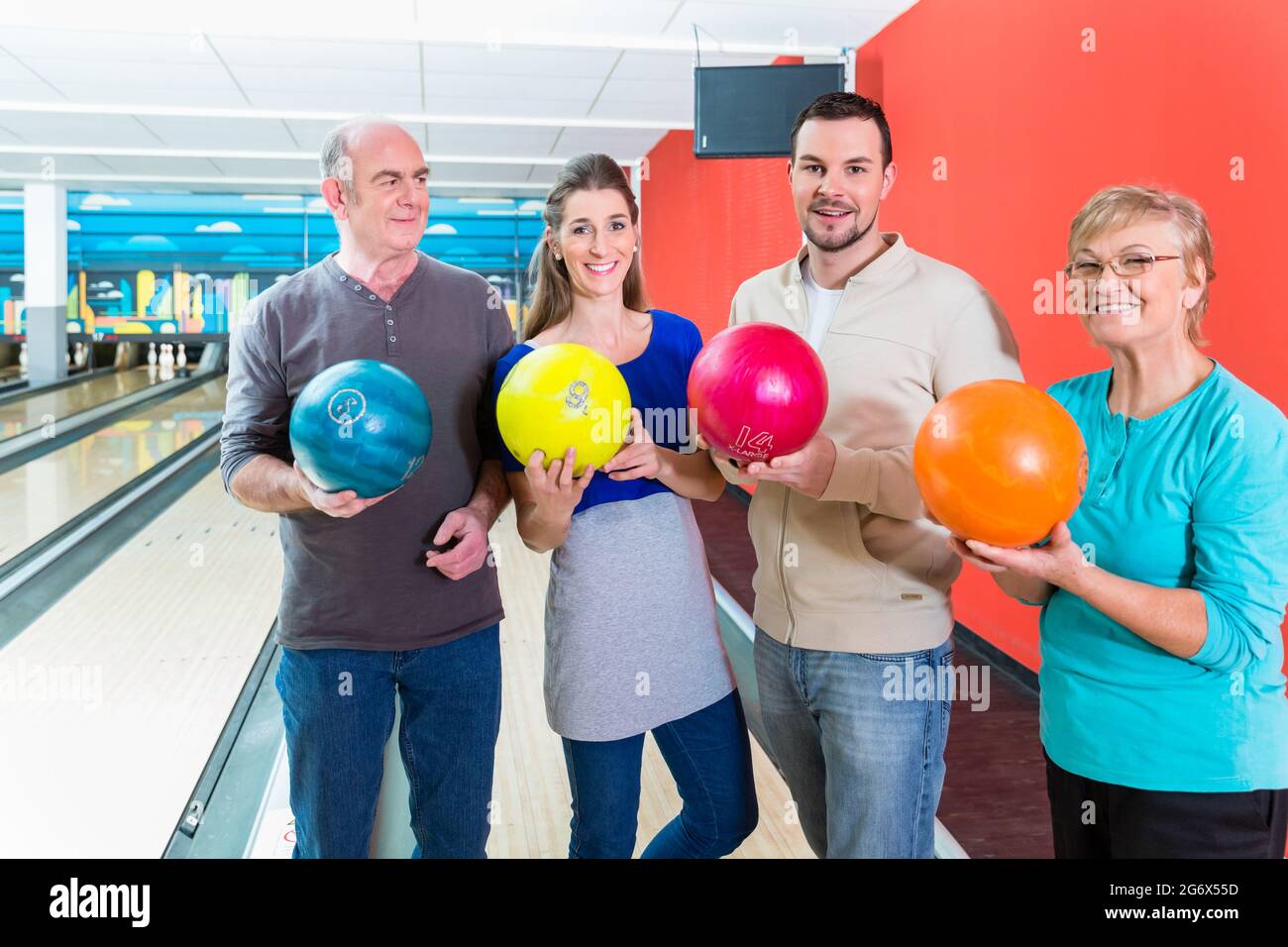 Smiling family holding multi colored bowling ball Stock Photo