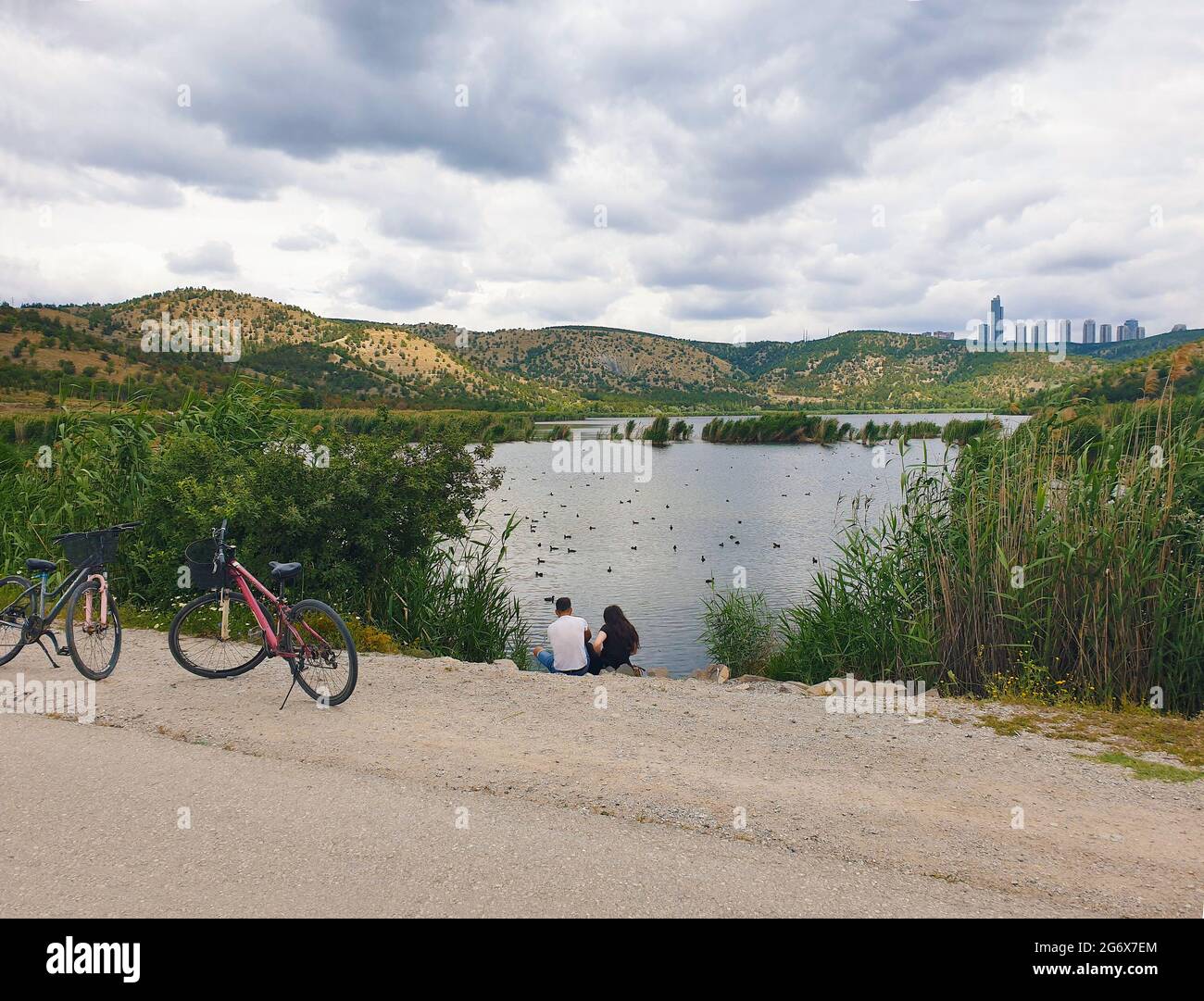 Ankara; Turkey-July 04; 2021: Couple sitting by the lakeside and viewing beautiful view and in Lake Eymir in Ankara. People getting used to new normal Stock Photo