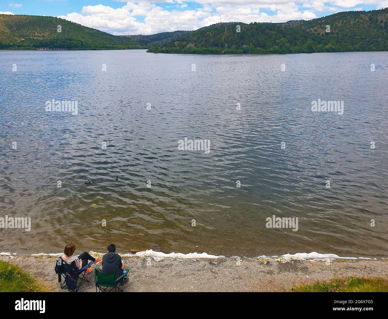 Ankara; Turkey-July 04; 2021: Mother and son sitting by the lakeside and relaxing in Ankara. People taking fresh air in Lake Eymir in Ankara. Stock Photo