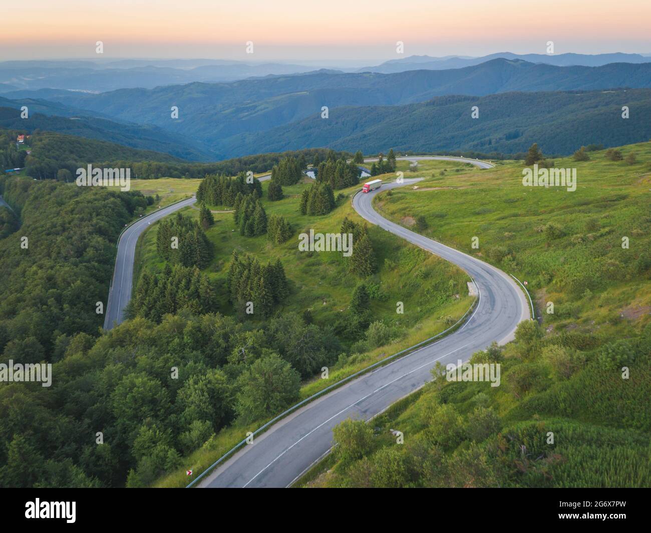 Drone follows Big truck delivering on asphalt mountain road Stock Photo