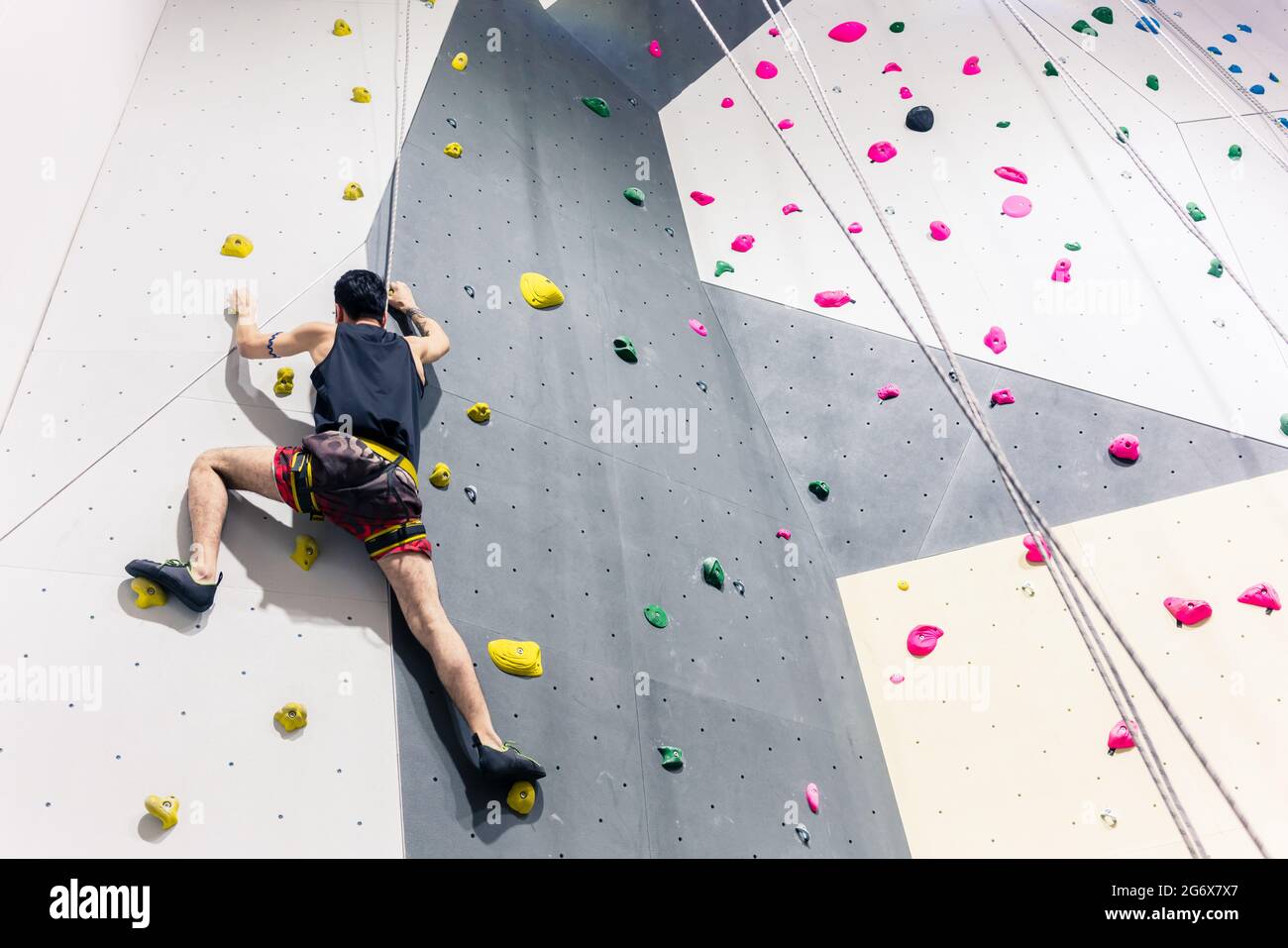 Rear view of man climbing wall with help of grip Stock Photo - Alamy