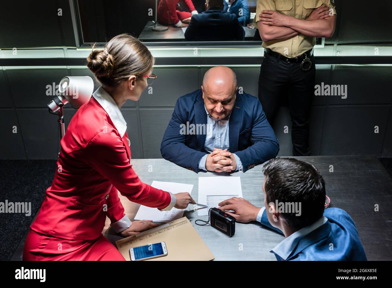 Middle-aged man thinking about his statement and the criminal charge while sitting down during interrogation in the office of the police station Stock Photo
