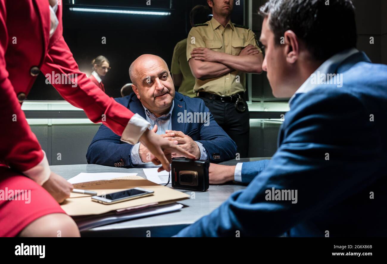 Middle-aged man thinking about his statement and the criminal charge while sitting down during interrogation in the office of the police station Stock Photo
