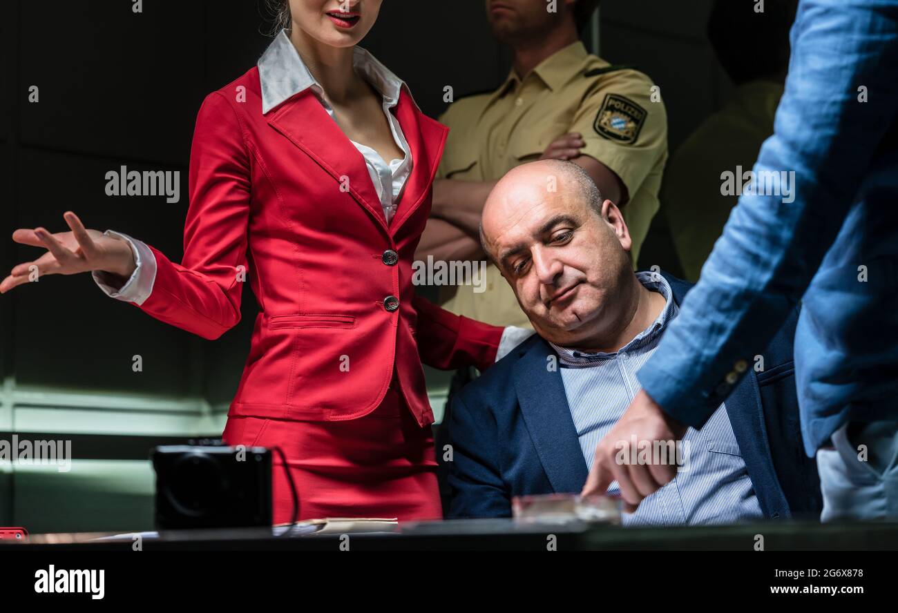 Middle-aged defendant using the right to remain in silence while listening to the charges of the prosecution during an aggressive interrogation at the Stock Photo