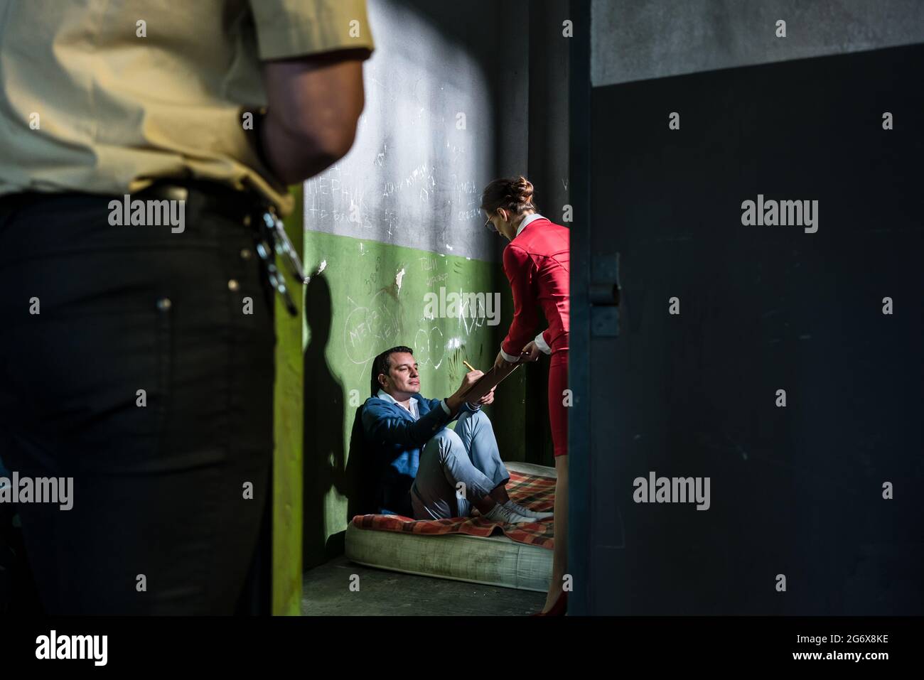 Dedicated female attorney visiting a young male inmate while helping him with the legal procedures in an obsolete prison cell during custody Stock Photo