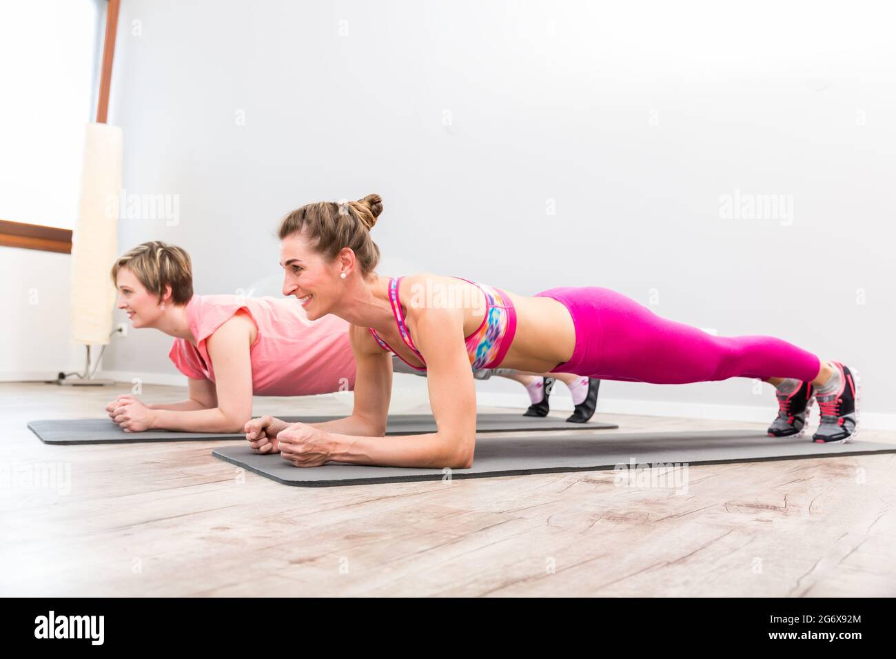 Two happy female friend doing yoga on exercise mat in class Stock Photo