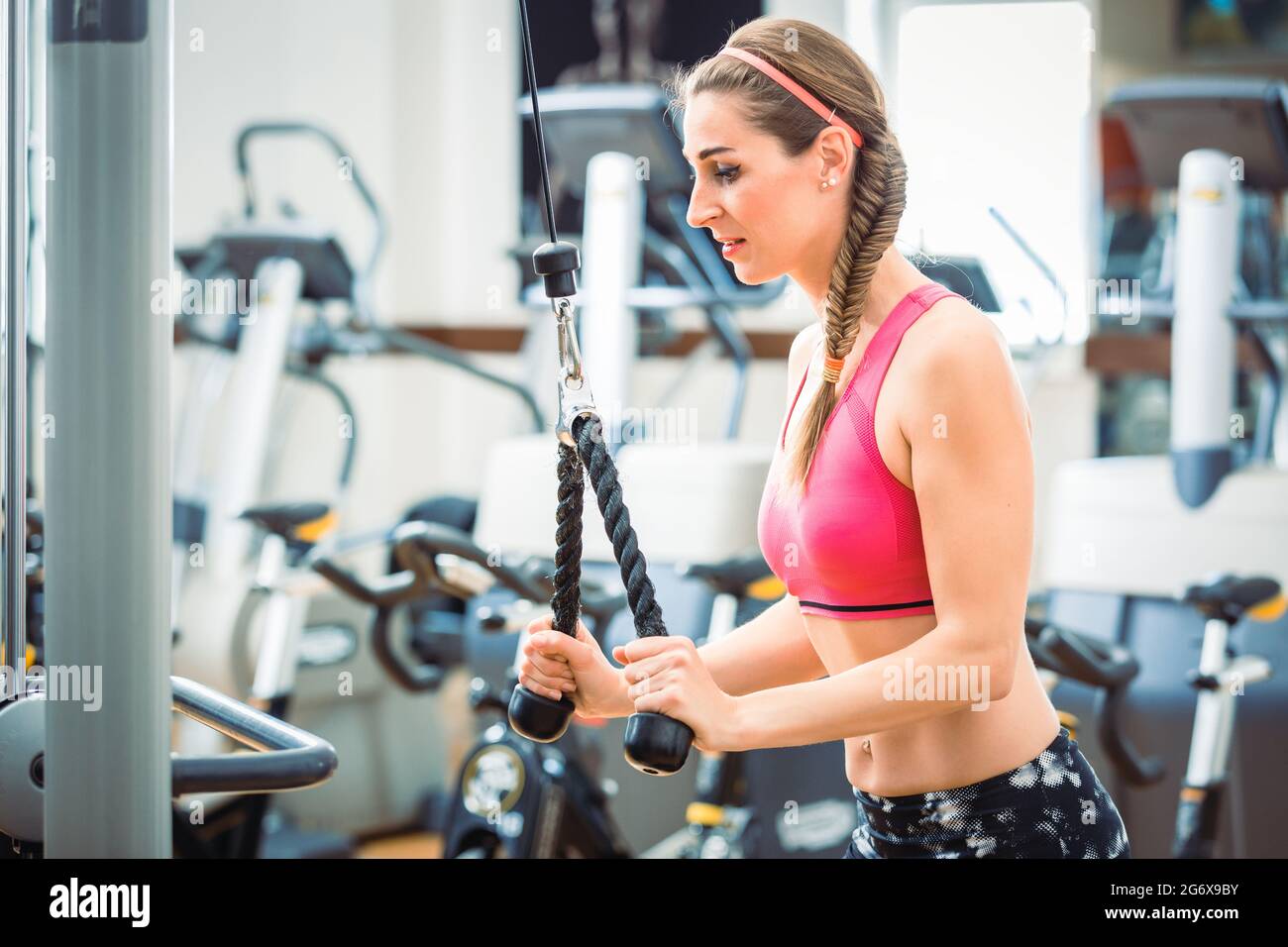 https://c8.alamy.com/comp/2G6X9BY/happy-and-beautiful-fit-woman-wearing-pink-fitness-bra-while-exercising-cable-rope-triceps-extension-at-the-gym-2G6X9BY.jpg