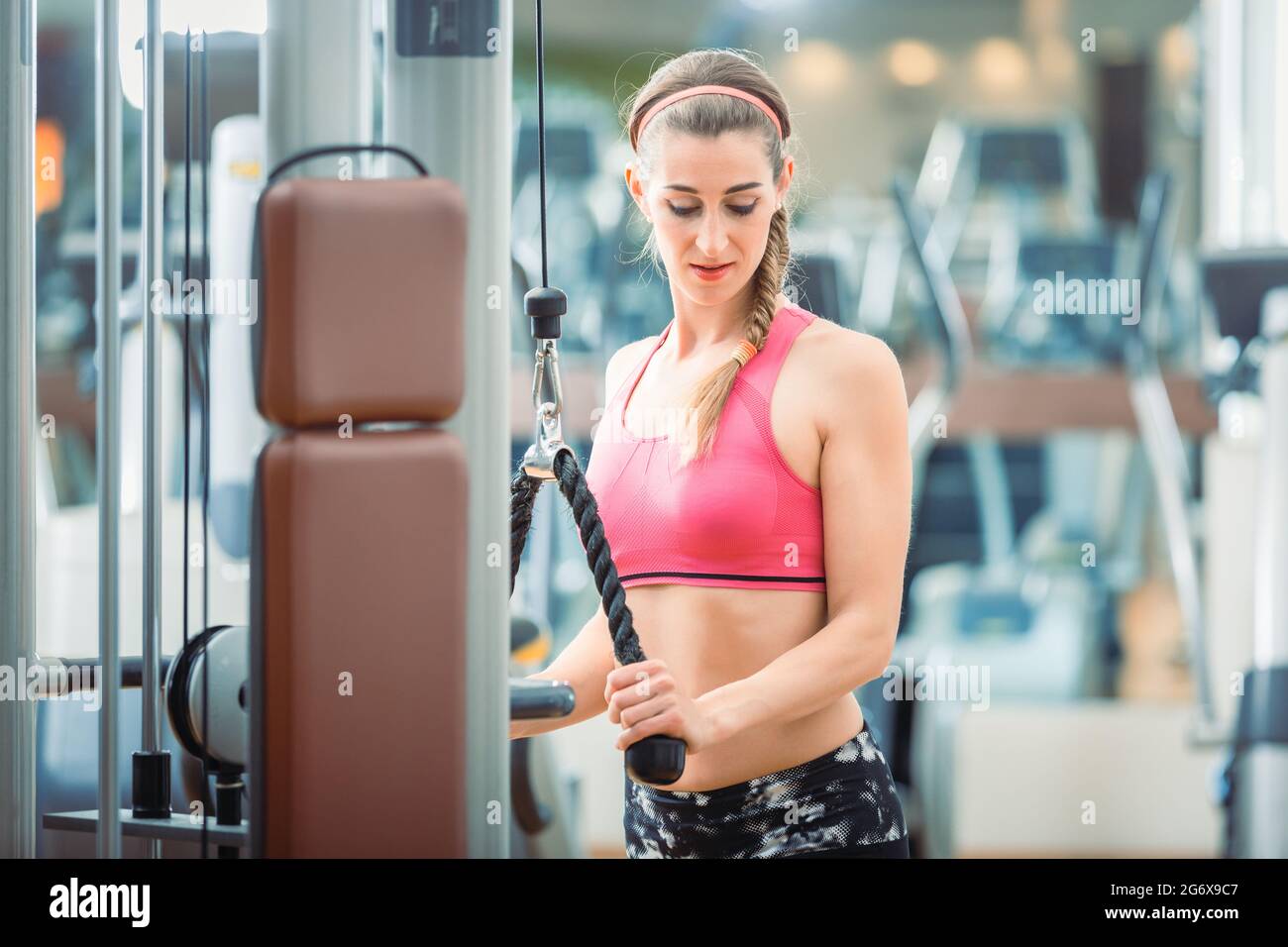 Happy and beautiful fit woman wearing pink fitness bra while exercising  cable rope triceps extension at the gym Stock Photo - Alamy