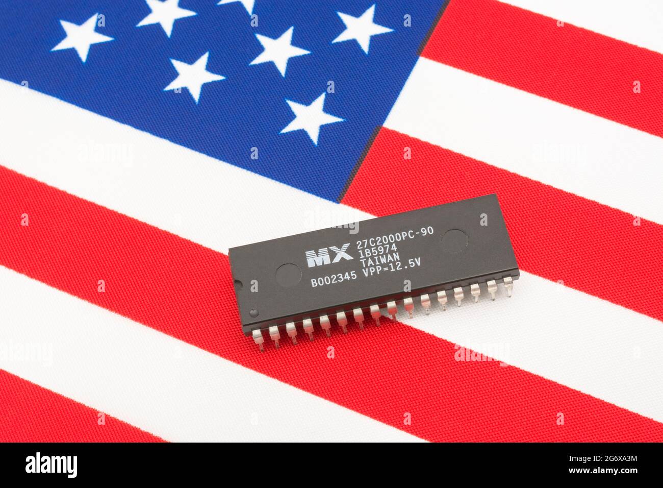 Close shot of Macronix International integrated circuit / EPROM chip on small US Stars & Stripes flag. For US semiconductor shortages in 2021. Stock Photo