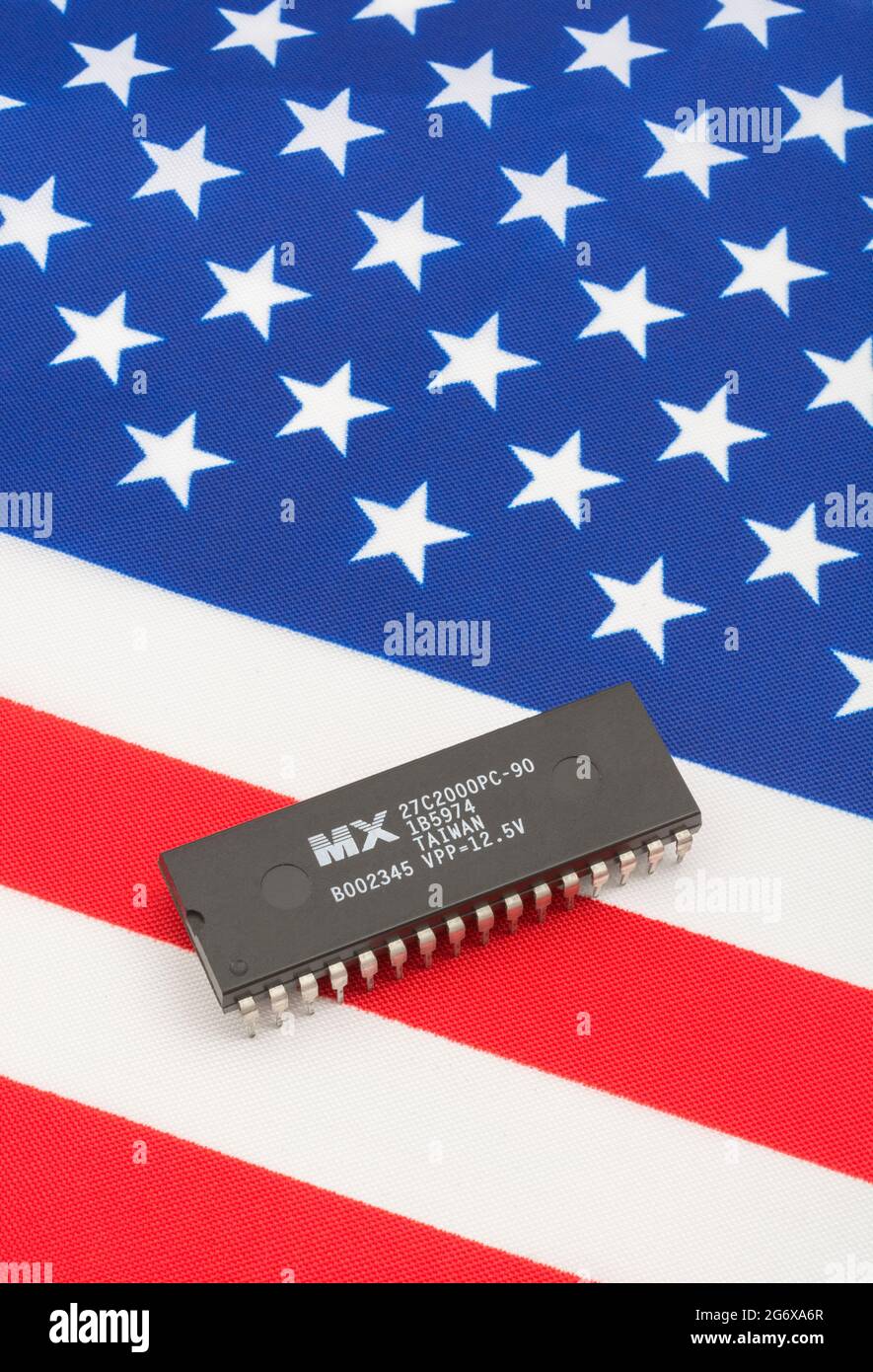 Close shot of Macronix International integrated circuit / EPROM chip on small US Stars & Stripes flag. For US semiconductor shortages in 2021. Stock Photo