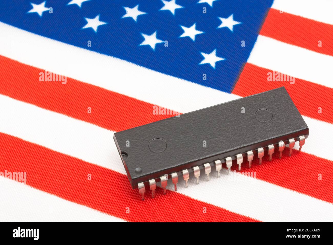 Close shot of integrated circuit / EPROM chip on small US Stars & Stripes flag. For US semiconductor shortages in 2021, American chip supremacy. Stock Photo