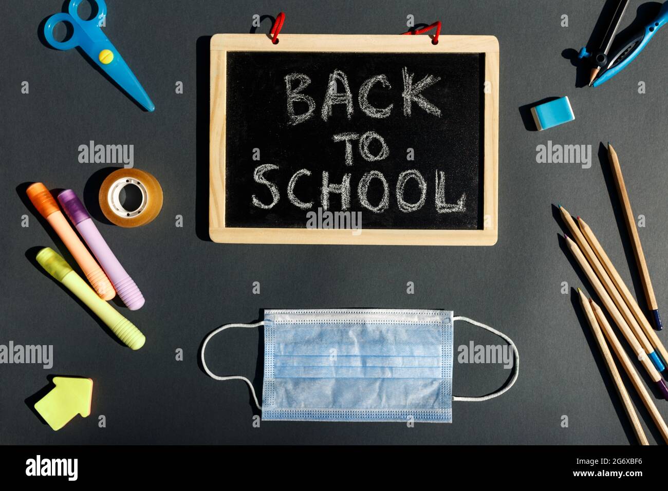 E- learning,Online education, School stationery supplies, medical mask, social distancing, school reopening. Back to school after covid-19 pandemic. New normal concept.Top view copy space,blackboard. Stock Photo