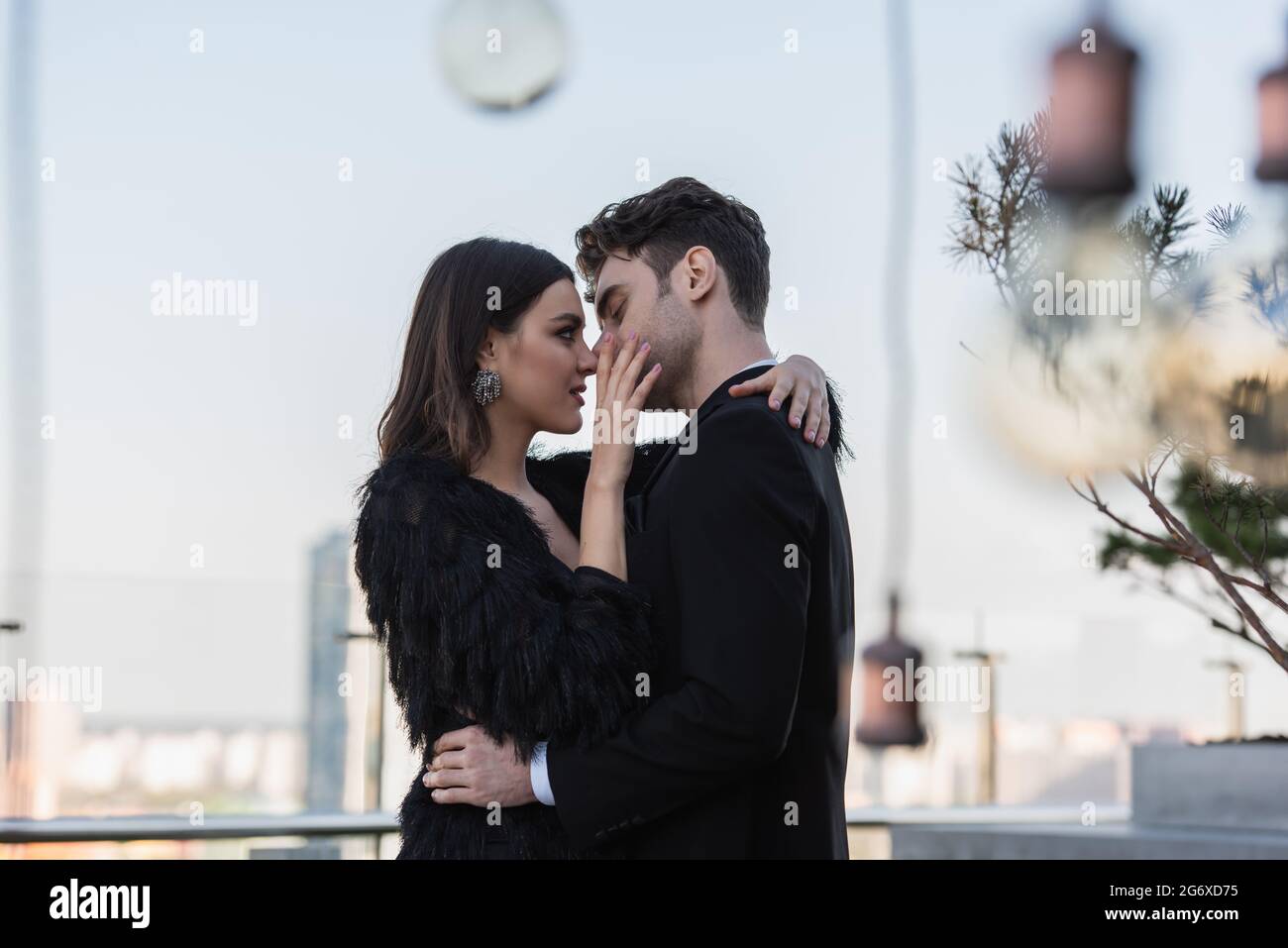 woman in faux fur jacket touch face and embracing man in suit outdoors ...
