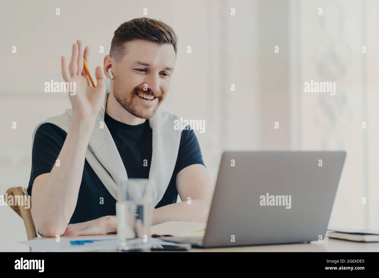 Happy male freelancer in wireless earphones having video call while ...