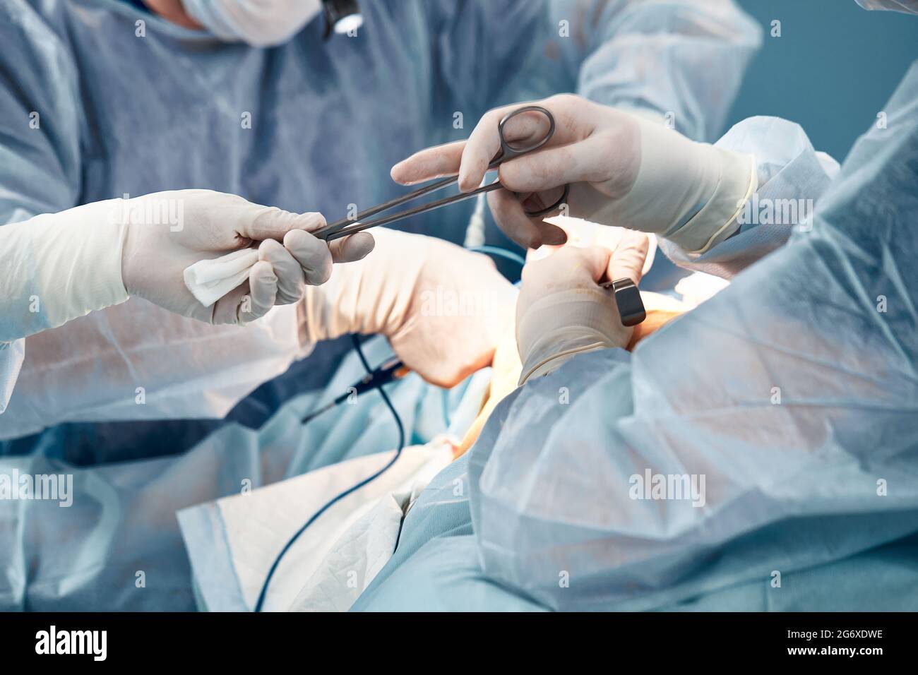 Hands of doctors in gloves during an operation, a close-up of an operating nurse gives a clamp to a surgeon, the styryl space is needed by a patient d Stock Photo