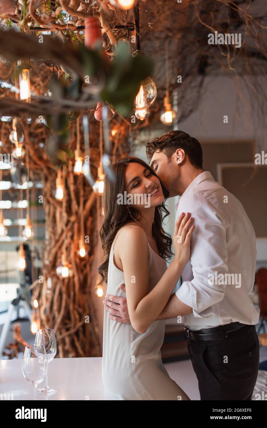 man kissing cheerful young woman in restaurant Stock Photo