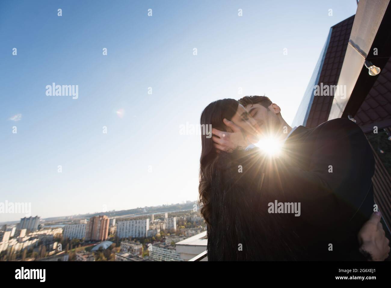 woman in faux fur jacket kissing with man on terrace Stock Photo
