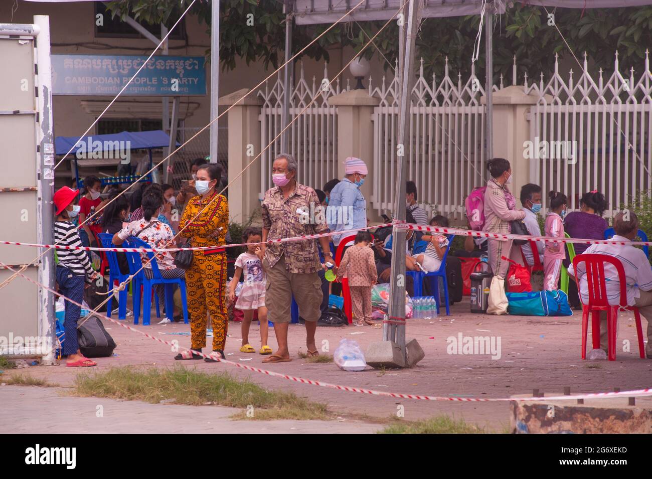 Phnom Penh, Cambodia. July 9th, 2021. for 4 months Phnom Penh has been battling a COVID - 19 surge. Cambodians, in protective face masks / coverings, that have tested positive for the virus wait for ambulances, with their bags packed, at a mass testing site. A Cambodian family w/ 2 young girls have all tested positive. Cambodians who test positive cannot leave the testing site & need to call a friend or a relative to pick up their personal belongings for the 2 week stay in the hospital. credit: Kraig Lieb / Alamy Live News Stock Photo