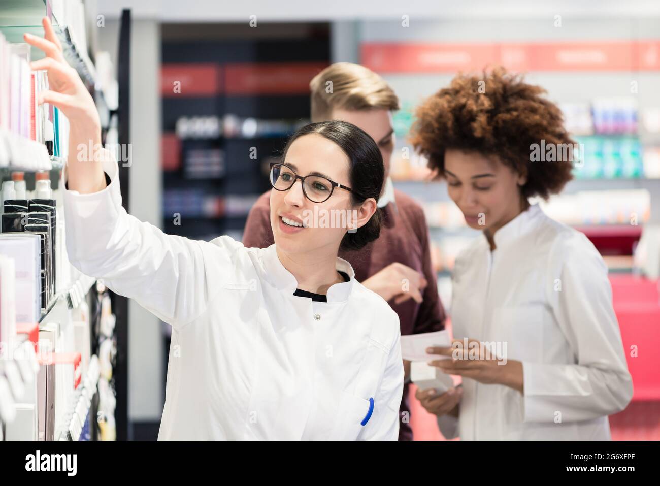 Portrait of a female experienced pharmacist reading the indications from the package of a new pharmaceutical product during work in a contemporary dru Stock Photo