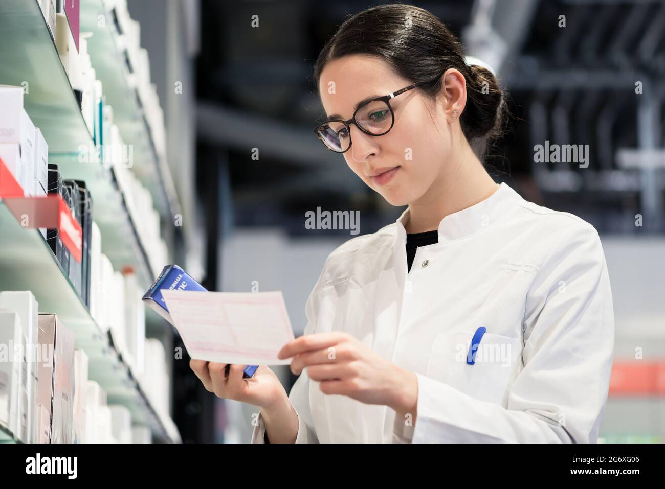 Low-angle portrait of an experienced female pharmacist checking the medical prescription of a pharmaceutical drug, while working in the interior of a Stock Photo