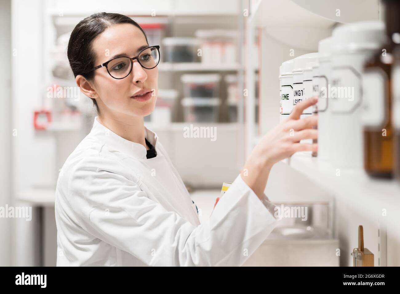 Side view of an experienced female pharmacist checking the container of a chemical pharmaceutical substance during inventory in a modern drugstore Stock Photo