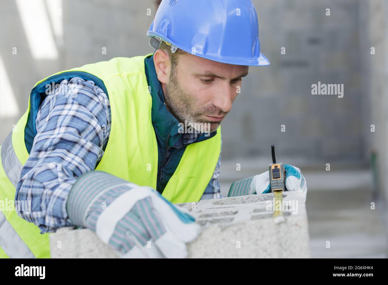 portrait of a builder measuring blocks Stock Photo - Alamy