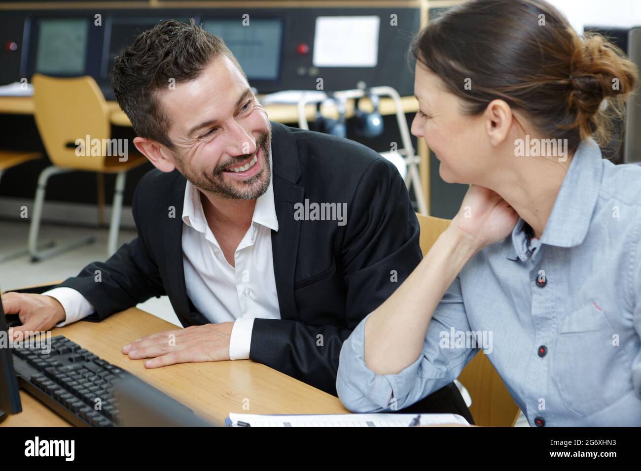male and female colleagues happily working at computer desk Stock Photo ...