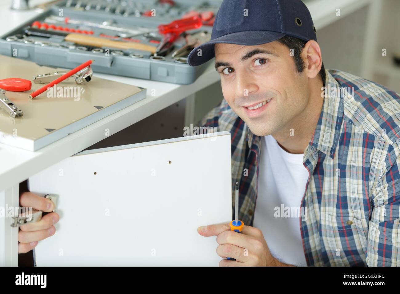 handyman fixing a door in a kitchen Stock Photo Alamy