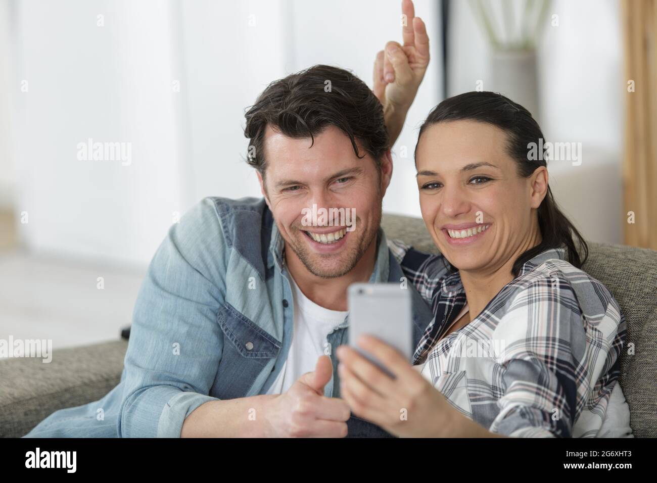 happy couple taking a selfie while sitting on a couch Stock Photo - Alamy