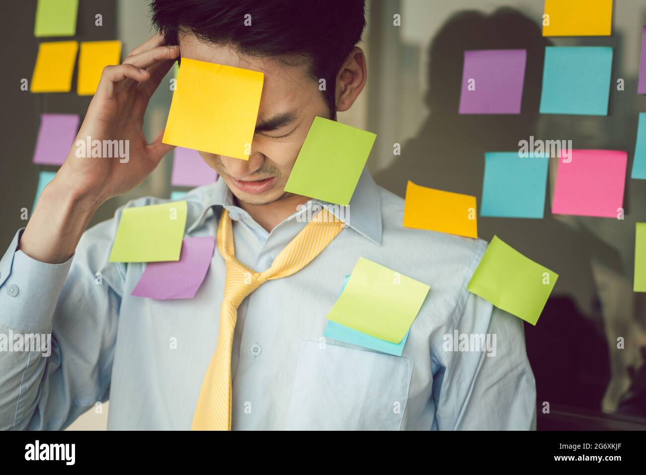 Portrait of stressful young businessman with colorful adhesives notes on his body Stock Photo