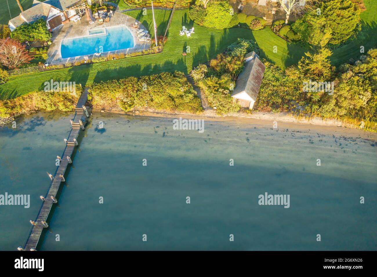 Aerial of a luxury property with a long dock, boathouse, pool and formal gardens. Stock Photo