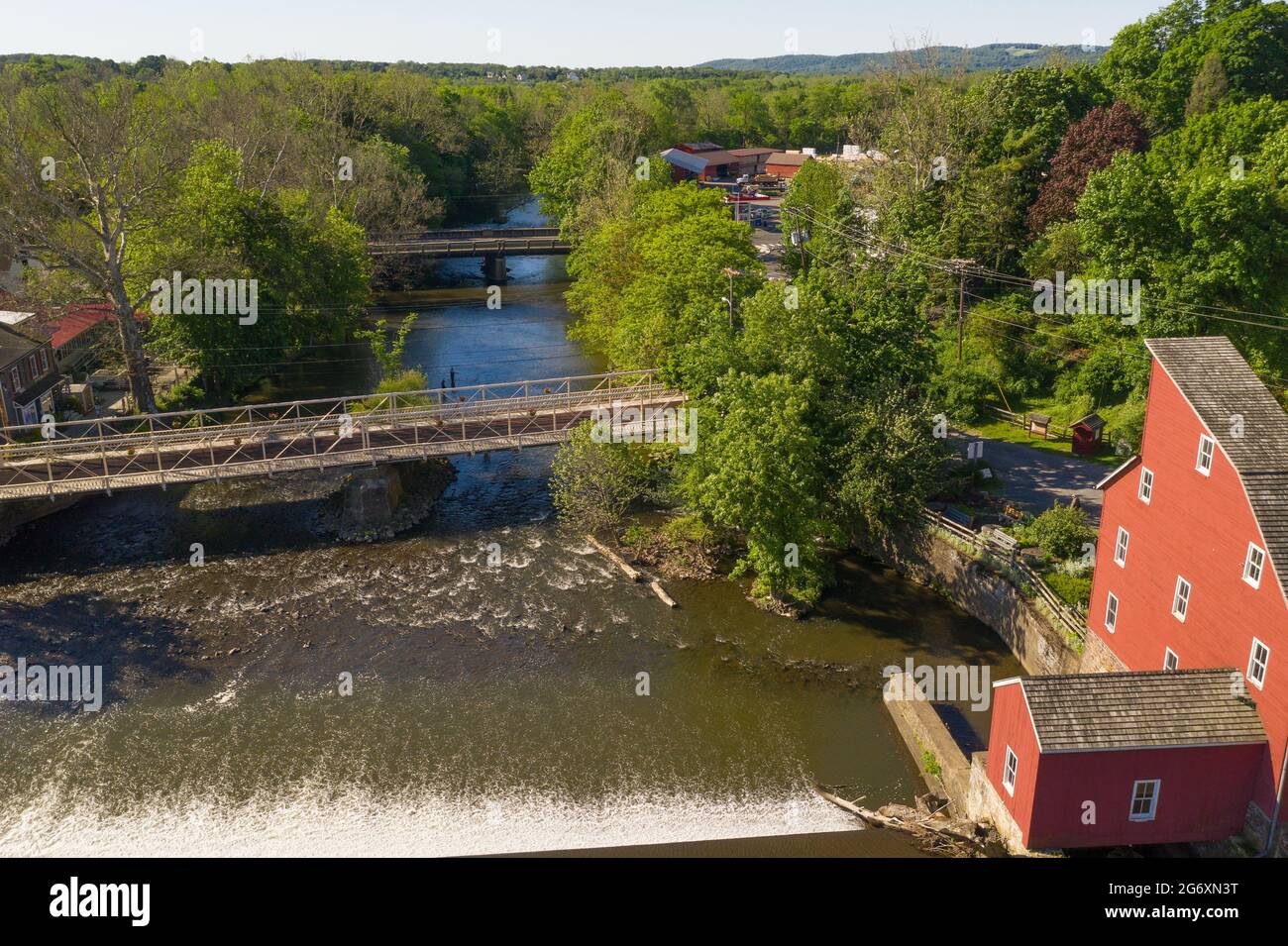 Aerial of an old red mill in Clinton, New Jersey, a historic river town, with a waterfall in the foreground. Stock Photo