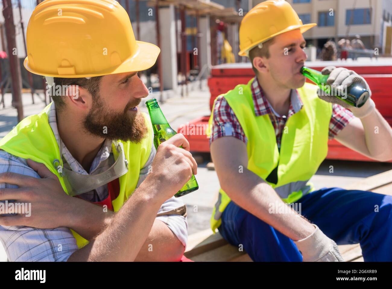 Two young workers smiling, while drinking a cold alcoholic or non