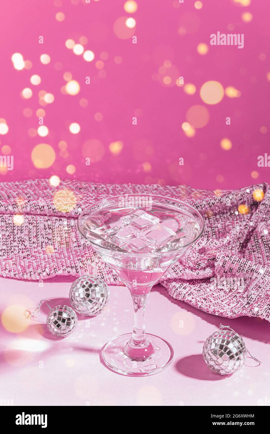 Martini cocktail pink festive background with shiny disco balls. An