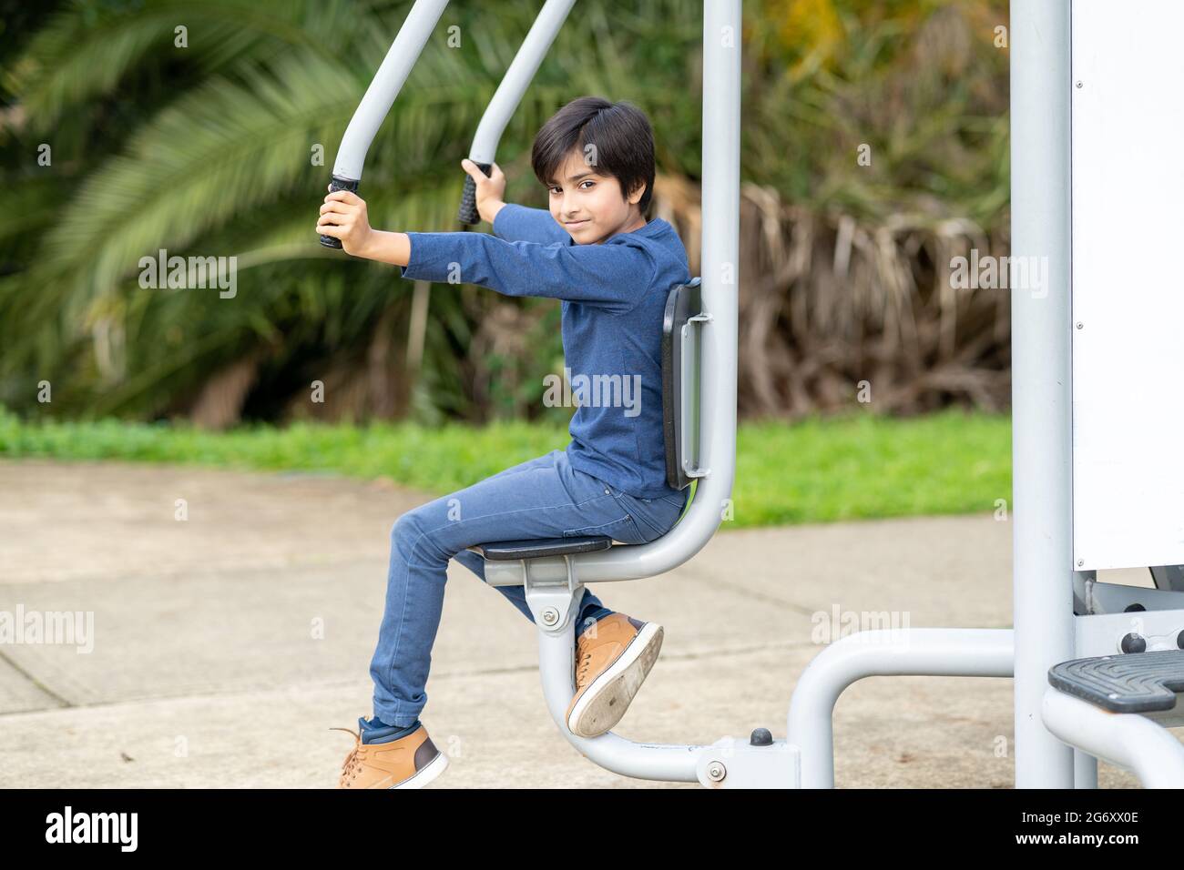Healthy kid doing exercise on gym equipment at park. Fitness concept. Active Young boy. Smart person at gym. Stock Photo