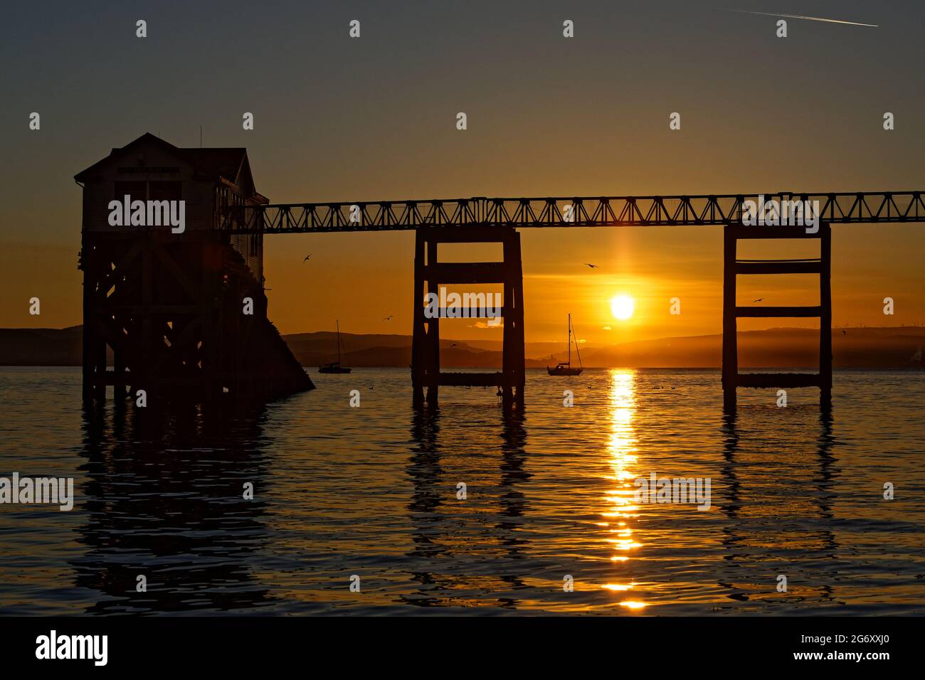 Pictured: Sunrise as seen through the RNLI boat station in Mumbles, near Swansea, Wales, UK. Sunday 13 June 2021 Re: High temperatures and sunshine ha Stock Photo