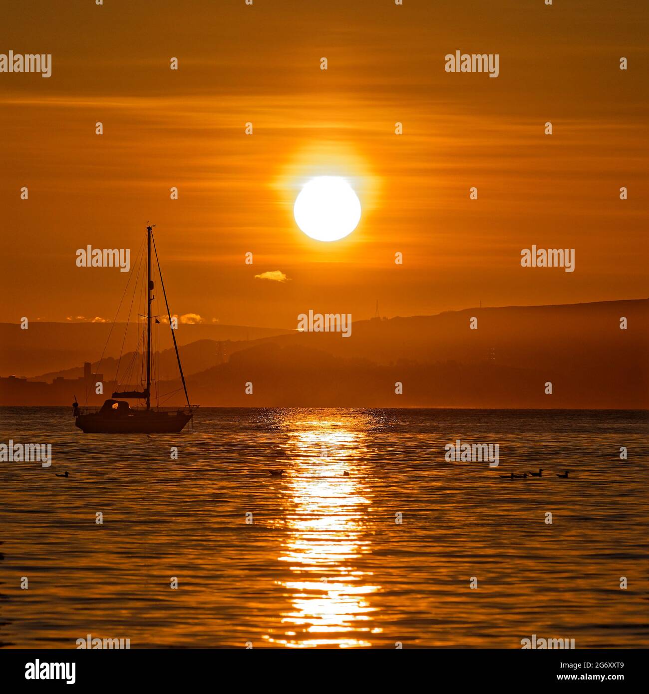 Pictured: Sunrise as seen through the RNLI boat station in Mumbles, near Swansea, Wales, UK. Sunday 13 June 2021 Re: High temperatures and sunshine ha Stock Photo
