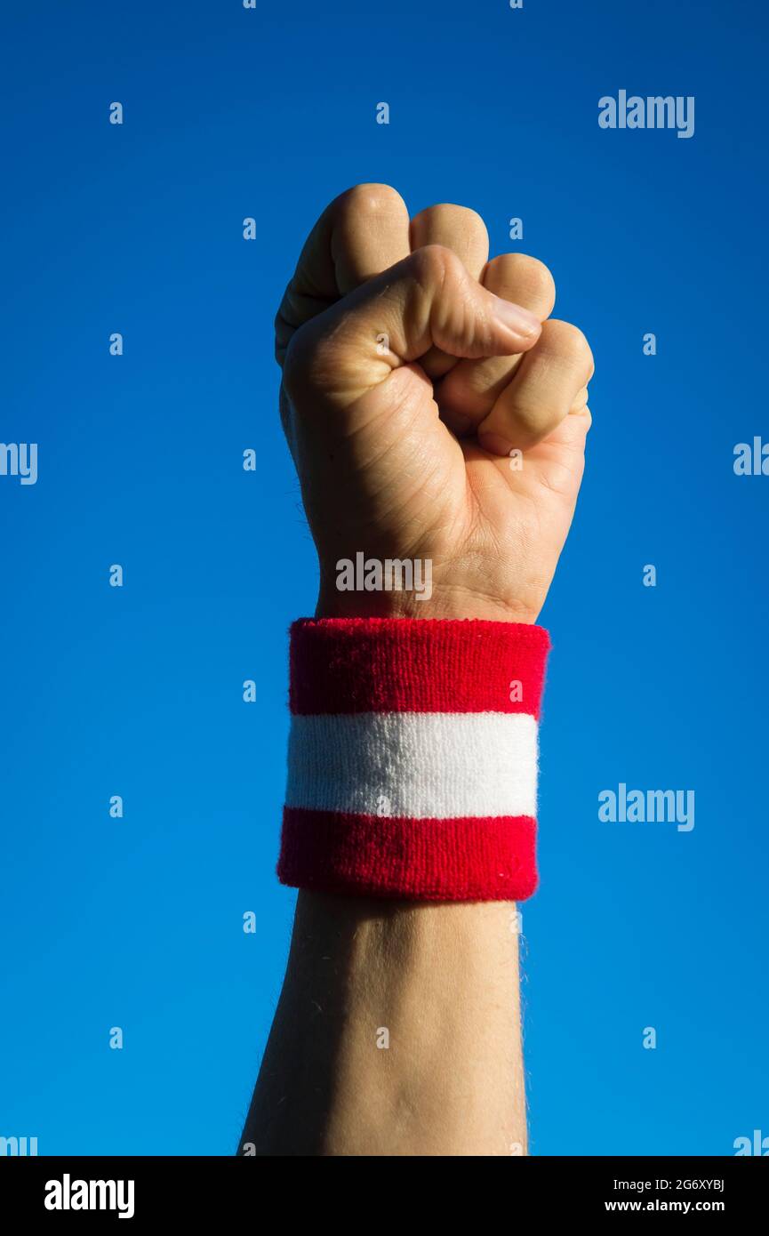 Japanese athlete punching the air with red and white wristband against bright blue sky Stock Photo