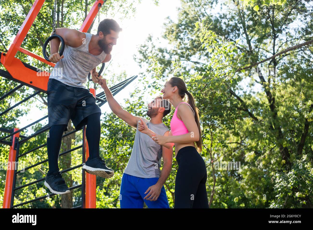 Lowangle view of a strong young man doing difficult dip exercise for triceps on gymnastic rings
