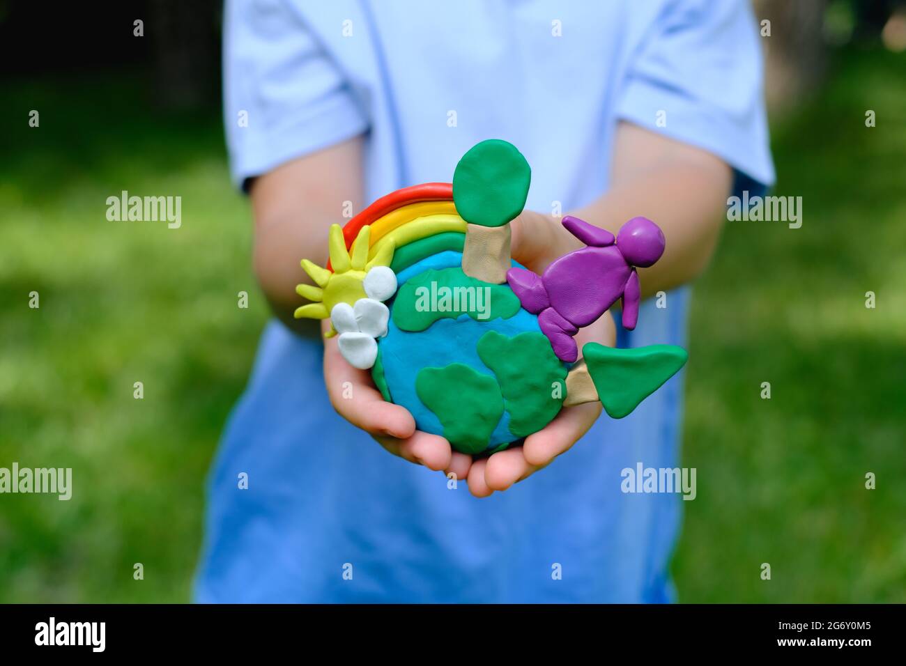 Environmental information and understanding. Child hands holding earth model with clay rainbow  Stock Photo