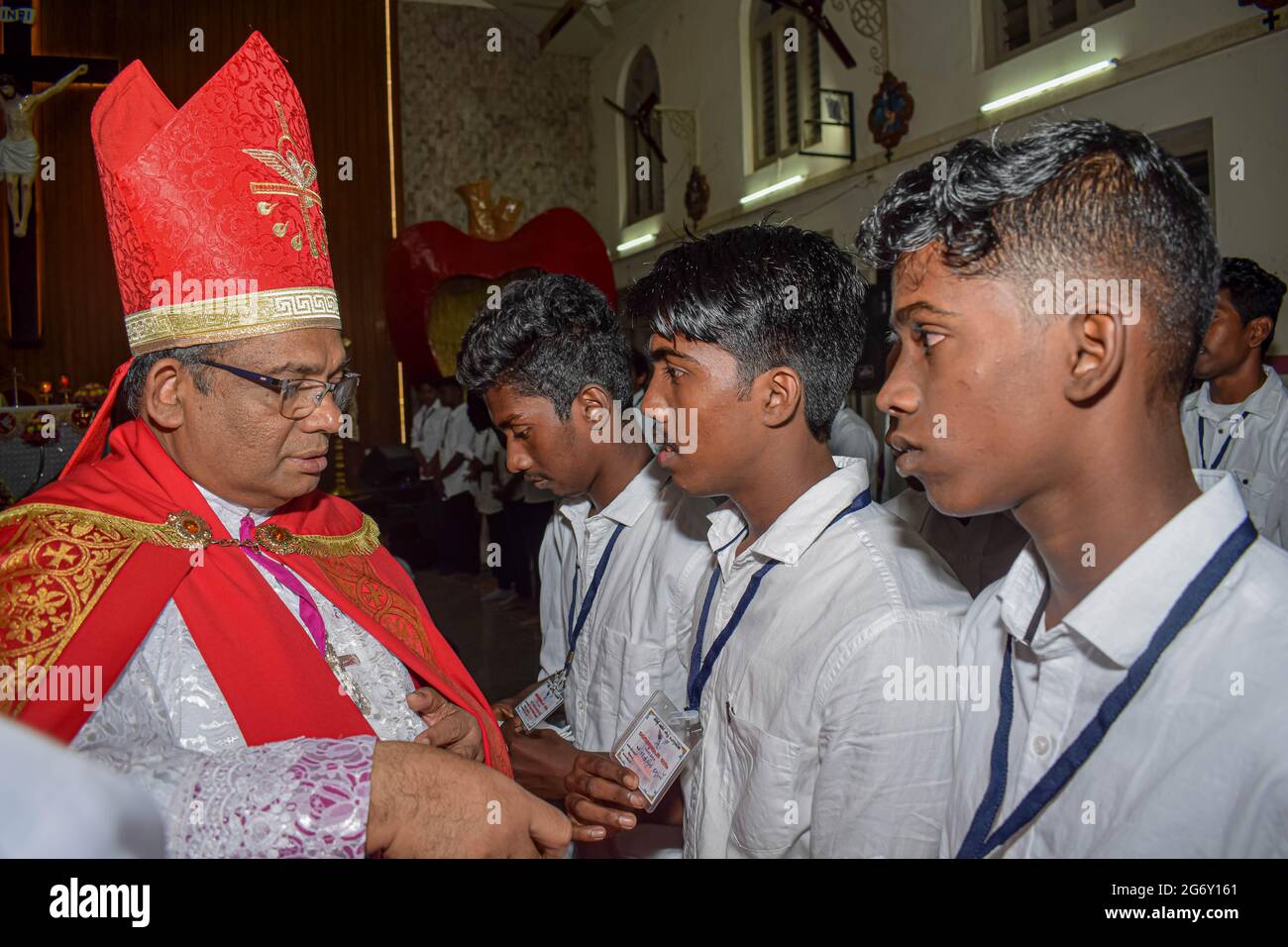 Bishop is giving confirmation sacrament to young teenagers. Stock Photo