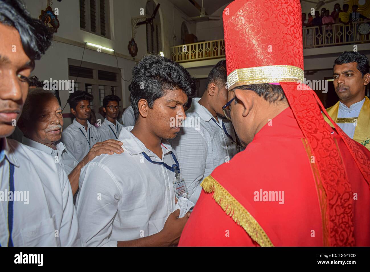 Bishop is giving confirmation sacrament to young teenagers. Stock Photo