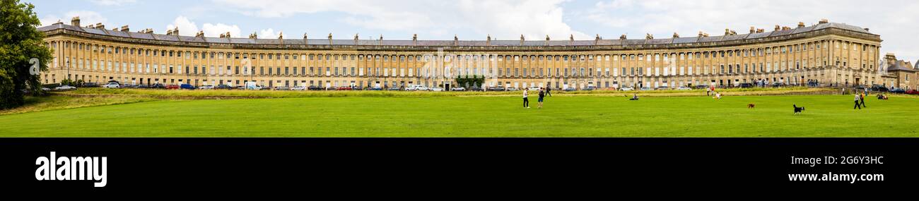 Tourists relax on the grass in front of a panoramic view of the Georgian Royal Crescent, Bath, Somerset, England. Stock Photo
