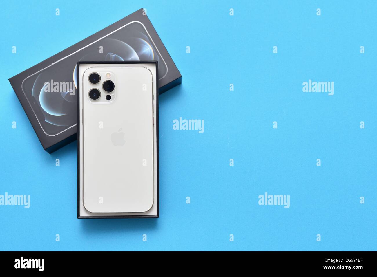 STARIY OSKOL, RUSSIA - JULY 5, 2021: New white iPhone 12 pro max in a box on a blue background with copy space Stock Photo