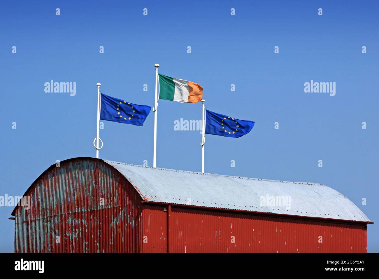 A red barn with European and an Irish flag, a metaphor on Euro and Irish farm issues. Stock Photo